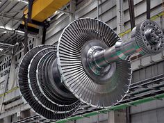 an airplane engine being worked on in a factory or assembly line, with the rotors still attached