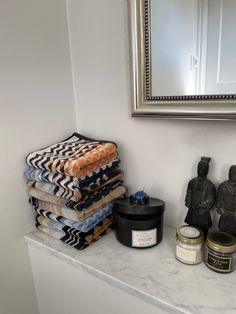 towels stacked on top of each other in front of a mirror and candle next to some figurines