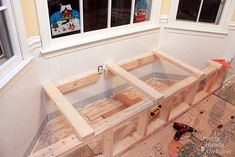 an unfinished bench sitting in front of a window with tools on the floor next to it