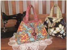 two purses sitting on top of a table next to a sewing machine