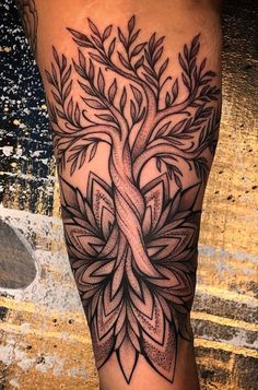 a black and white tree tattoo on the right leg, with an intricate design in the middle