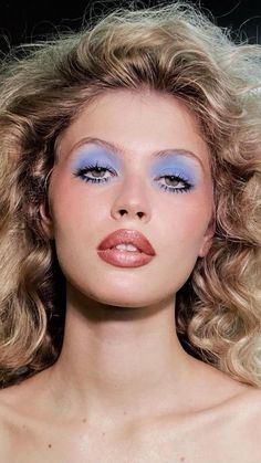 a woman with blonde hair and blue eyeshadow is posing for a fashion photo