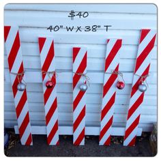 four red and white striped candy canes hanging from the side of a building with christmas ornaments on them