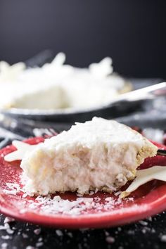 a piece of cake on a red plate covered in powdered sugar and icing