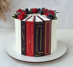 a cake decorated with books and berries on top