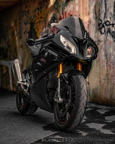 a black motorcycle parked in front of a graffiti covered wall