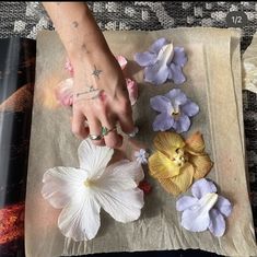 a person with tattoos on their hand and some flowers