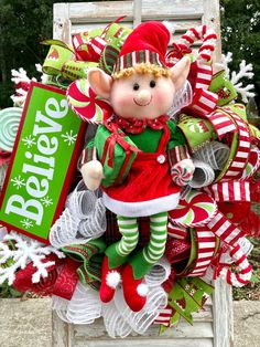 a christmas wreath with an elf doll sitting on top of it and holding a candy bar