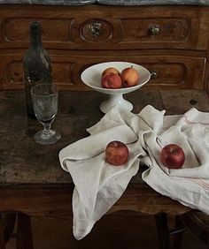 two apples are sitting on a table next to a wine glass and an empty bottle