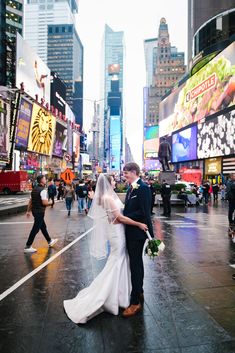 a bride and groom walking down the street in times square