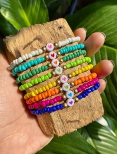 a hand holding a wooden block with colorful beads on it