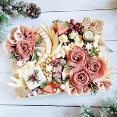 an assortment of cheeses, meats and vegetables on a platter with pine cones