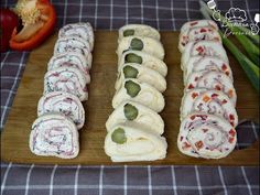 several different types of sushi on a cutting board next to tomatoes and celery