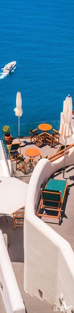 an outdoor seating area overlooking the ocean with chairs and umbrellas