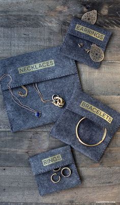 three pairs of jewelry sitting on top of a wooden table next to two bags with rings and earrings in them