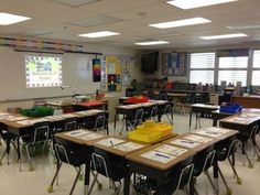 an empty classroom with desks and chairs in front of a projector screen on the wall