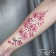 a woman's arm with pink flowers and leaves on the left side of her arm