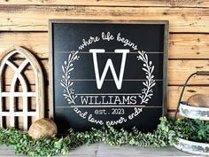 a wooden sign with the letter w on it and some greenery next to it