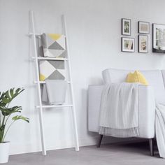 a living room with white furniture and pictures on the wall, including a ladder for towels