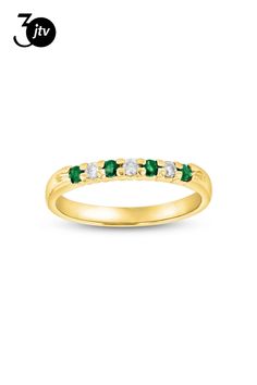 a yellow gold ring with green and white stones on the side, in front of a white