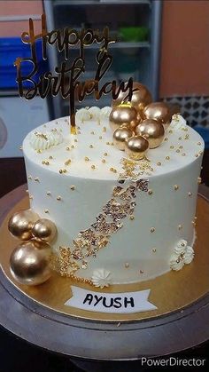 a white cake with gold decorations and a happy birthday sign on it's top