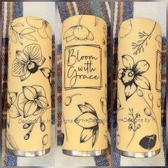 three yellow candles with floral designs on them sitting on a plaid tablecloth covered surface