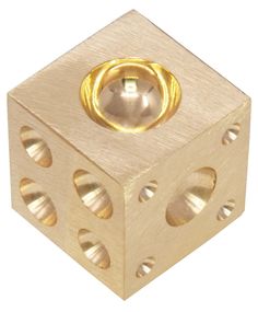 a wooden block with two holes and a gold ring on the top, in front of a white background