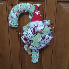 a christmas wreath on the front door with santa claus's hat hanging from it