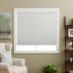 a living room with a chair, window and pictures on the wall above it that has blinds