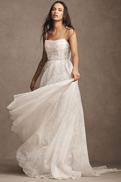 a woman in a white dress is posing for the camera with her long flowing skirt