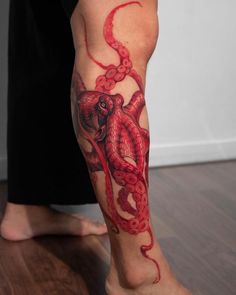 an octopus tattoo on the leg of a person with red ink and watercolors