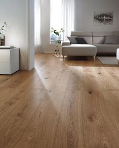 a living room with white furniture and wood floors