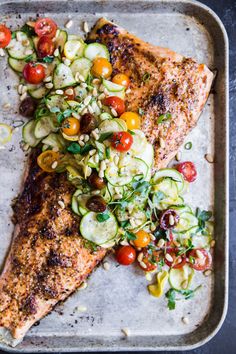 grilled salmon with zucchini, tomatoes and cucumbers on a baking sheet