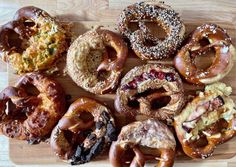 a wooden cutting board topped with lots of different types of doughnuts and pretzels