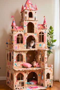 a cat is sitting on top of a cardboard doll house that has been made into a castle