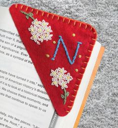 a red triangle bookmark with flowers on it sitting on top of an open book