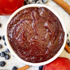 a white bowl filled with fruit next to cinnamons and blueberries on a table