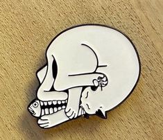 a white and black pin with a skull on it