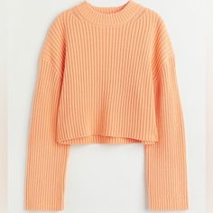 an orange cropped sweater is hanging on a hanger, with the top half open