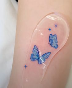 two blue butterflies sitting on the side of a woman's thigh with stars around it