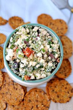 a bowl filled with salad next to crackers