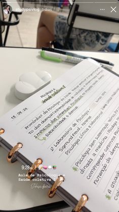 an open notebook sitting on top of a table next to a pair of gold rings