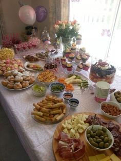 a table filled with lots of food on top of a white table covered in balloons