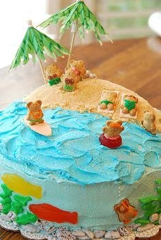 a cake with blue frosting and teddy bears on it sitting on top of a table