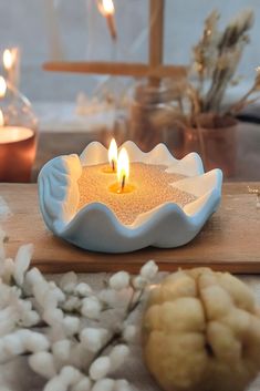 a lit candle sitting on top of a wooden table next to cotton balls and candles