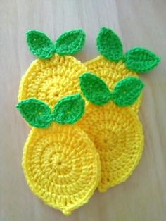 two crocheted lemons with green leaves on them