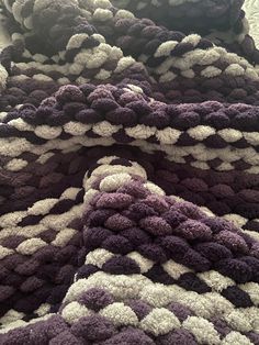 a pile of purple and white crocheted rugs