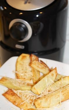 some french fries on a white plate next to an electric crock pot