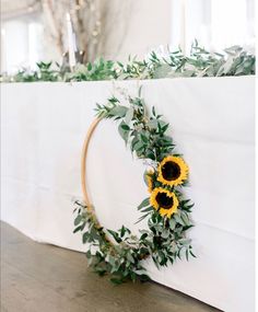 sunflowers and greenery are arranged on the back of a white table cloth