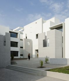 a person standing in front of a white building with stairs leading up to the entrance